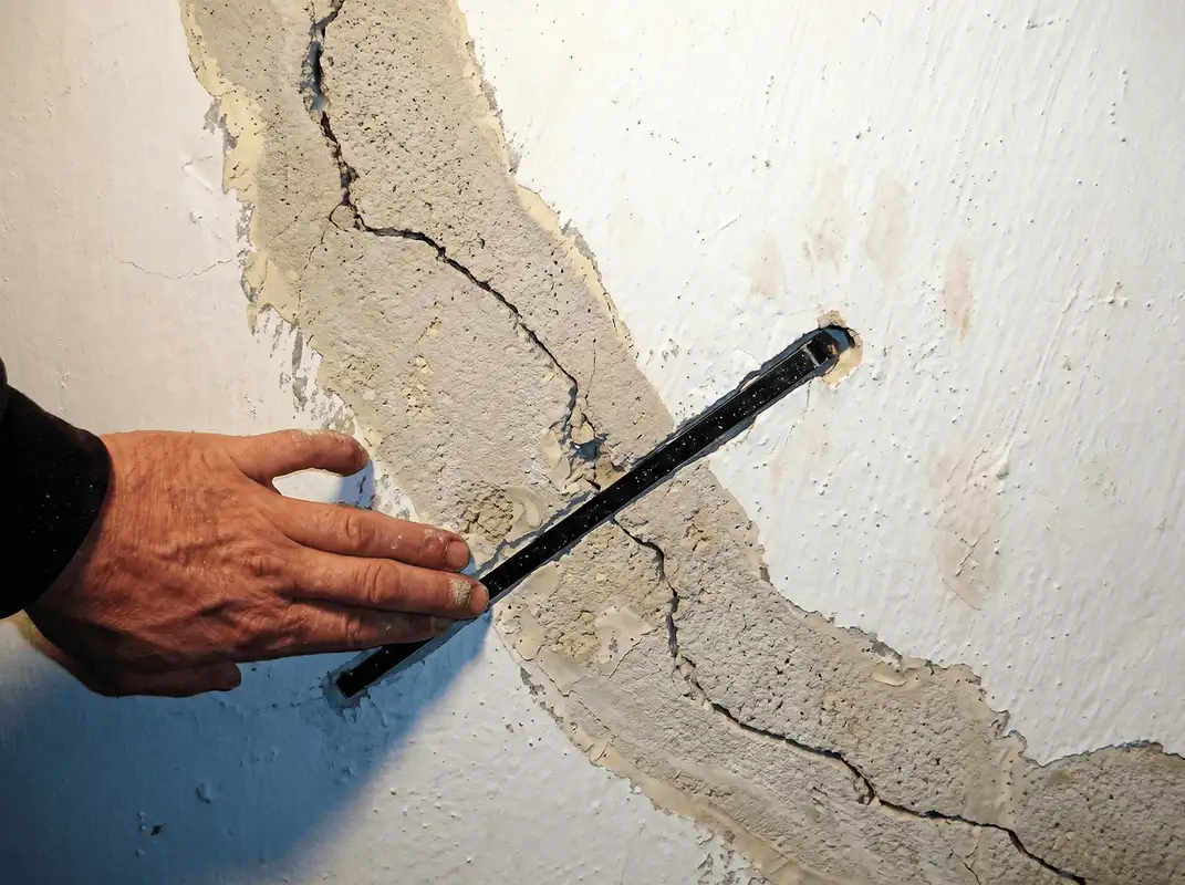 A wall with a large crack is being inspected by a professional in Wichita, KS