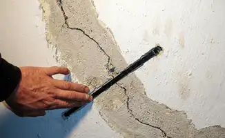 A wall with a large crack is being inspected by a professional in Wichita, KS